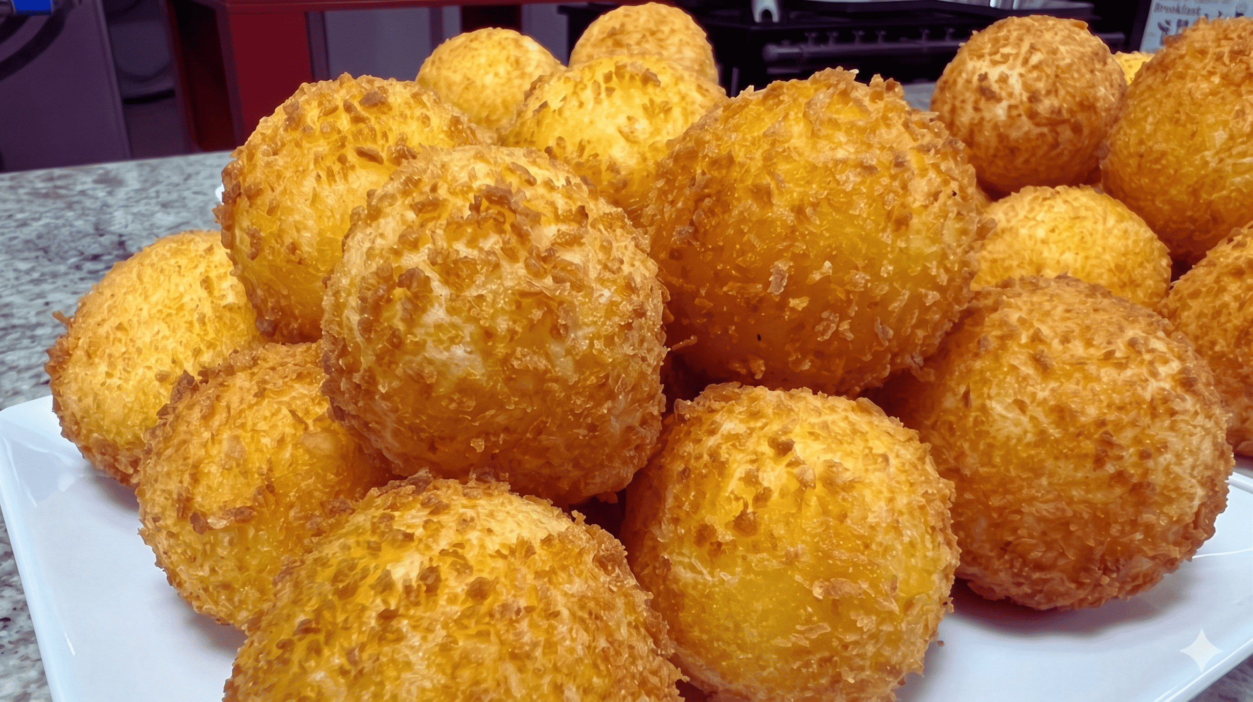 Bolinho de queijo com massa de mandioca empanado em panko, dourado e crocante, servido em pirâmide
